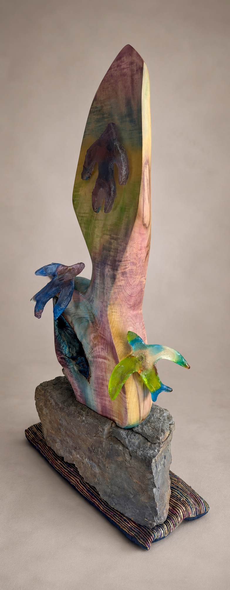 Detailed view of individually cast cobalt blue, grey, copper blue, lime green and citrine crystal-glass swifts against a warm-grey studio background