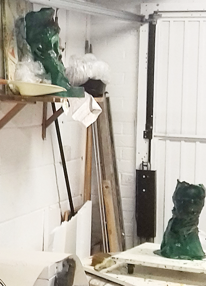 Two green wax forms of the Swifts sculptures displayed in the workshop